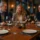 Elegancki drewniany stół w restauracji z nakryciem stołu, oświetlony naturalnym światłem, z gośćmi w tle - ilustracja jakości i trwałości mebli gastronomicznych.